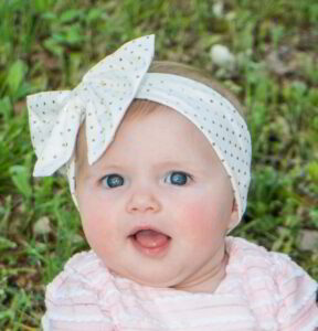 A baby girl wearing a pink and white polka dot headband.